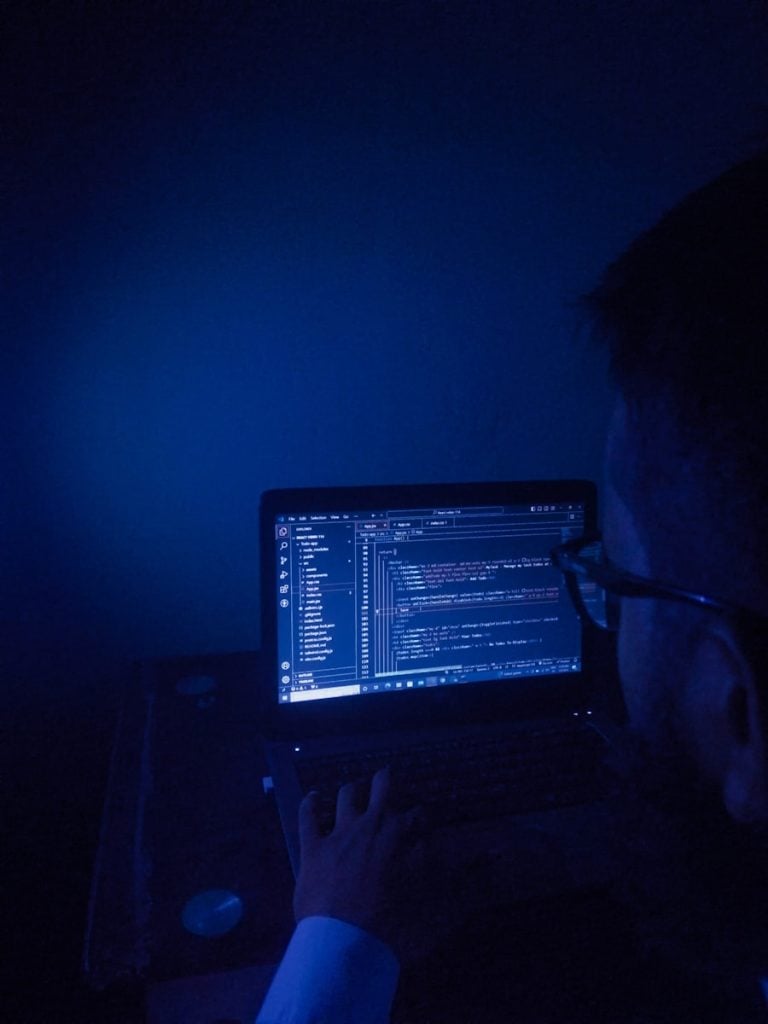 A man sitting in front of a laptop computer in a dark room