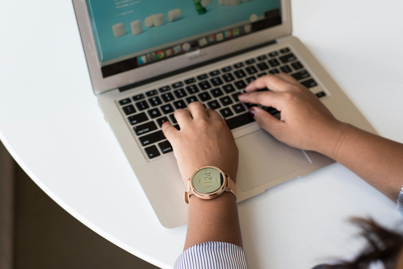 person using MacBook on white table